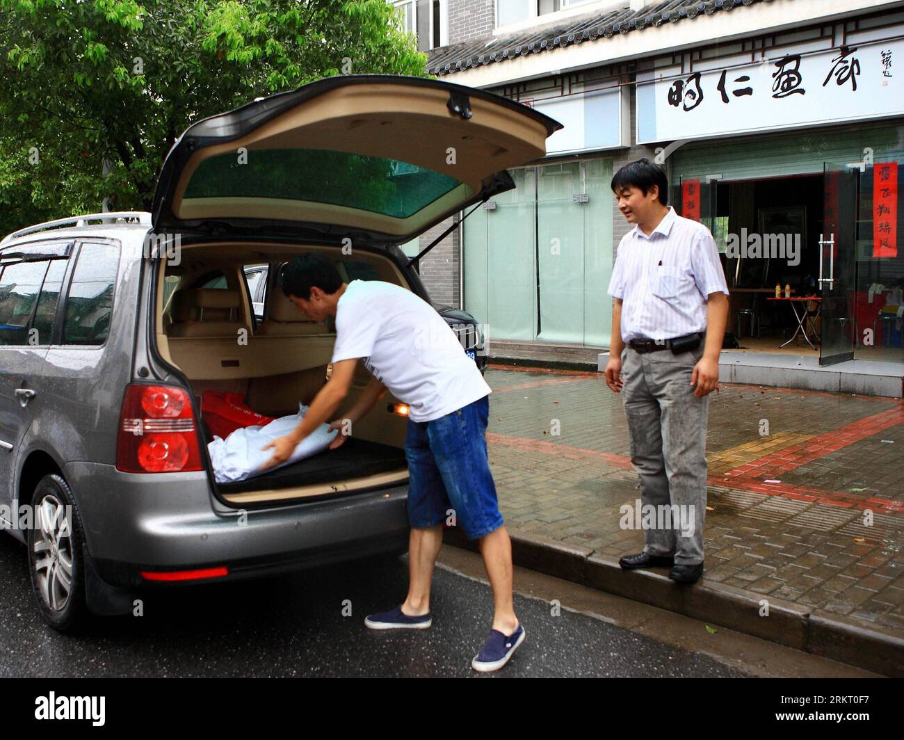 Bildnummer: 58338525 Datum: 12.08.2012 Copyright: imago/Xinhua (120812) -- HEFEI, 12. August 2012 (Xinhua) -- Ein Mitarbeiter in einer Galerie hilft Xiang Sheah (R) beim Laden gerahmter Gemälde und Kalligraphien in das Auto im Bezirk Shexian der ostchinesischen Provinz Anhui, 8. August 2012. Der 43-Jährige Xiang Shdak führte die Handwerkskunst des Entwerfens und der Herstellung von Tintenstiften von seinem Vater fort, einem leitenden Handwerker in diesem Geschäft. Xiang begann 1987 sein eigenes Tintenstifthandel. Nach 20 Jahren Forschung und Entwicklung förderte Xiang die traditionelle Technologie und entwickelte eine Reihe neuer Musterdesigns. Währ Stockfoto