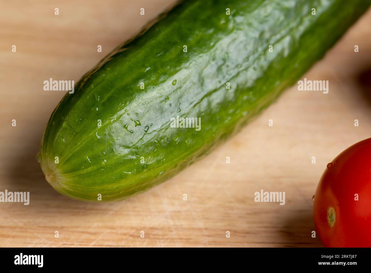 Geschnittene grüne lange Gurke während der Salatzubereitung, Salatzubereitung mit Gemüse in kleine Stücke grüne Gurken geschnitten Stockfoto