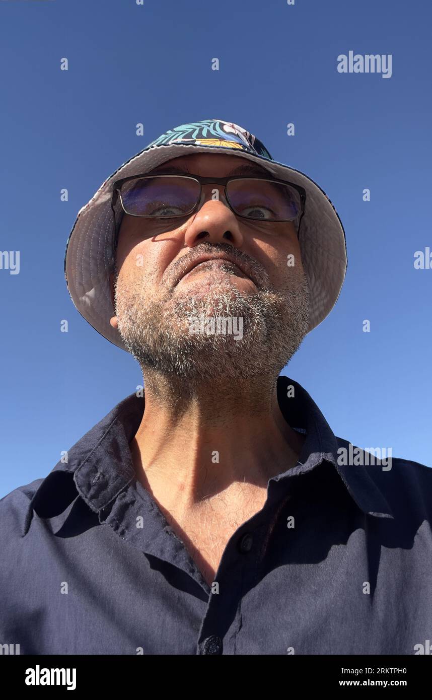 Porträt eines Mannes mittleren Alters am Meer mit buntem Hut Stockfoto