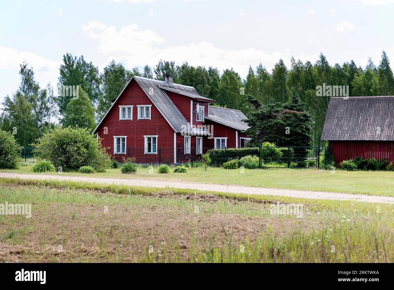 Traditionelles rotes altes Holzhaus im Südosten Estlands in ländlicher Umgebung vor Obinitsa, Estland Stockfoto