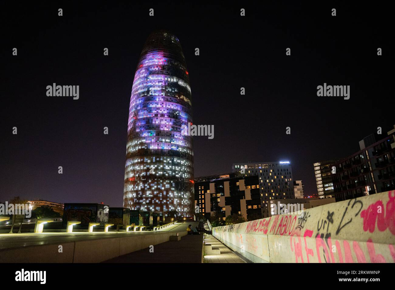 Barcelona, Barcelona, Spanien. 25. August 2023. Der beliebte Torre Agbar oder Torre de las Glorias in Barcelona wird in den Farben von ''La Vuelta'' in der Nacht vor der ersten Etappe der Vuelta EspaÃ±A 2023 beleuchtet. Die ersten beiden Etappen dieses Jahres verlaufen durch Barcelona, die wichtigste Stadt Kataloniens. (Bild: © Marc Asensio Clupes/ZUMA Press Wire) NUR REDAKTIONELLE VERWENDUNG! Nicht für kommerzielle ZWECKE! Quelle: ZUMA Press, Inc./Alamy Live News Stockfoto