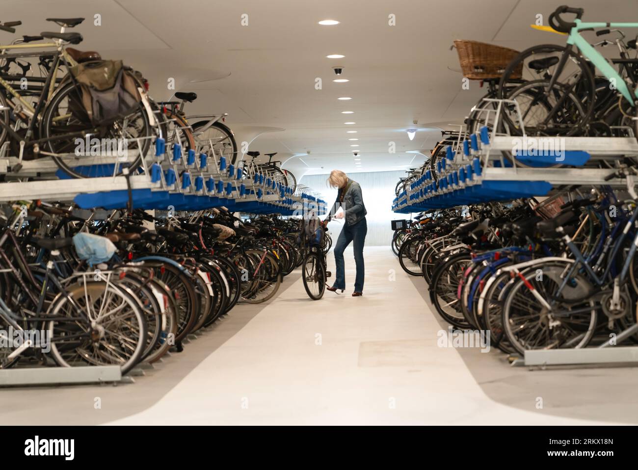Frau nimmt ihr Fahrrad von einer mehrstöckigen Tiefgarage am Hauptbahnhof, Amsterdam, Holland Stockfoto