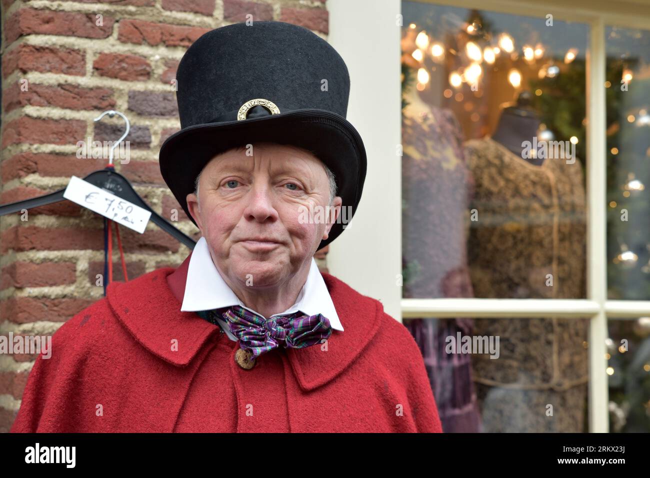 Ein älterer Gentleman mit Hut, rotem cape, weißem Kragen und farbenfroher Schleife spielt seine Rolle während des Dickens Feast in Deventer Stockfoto