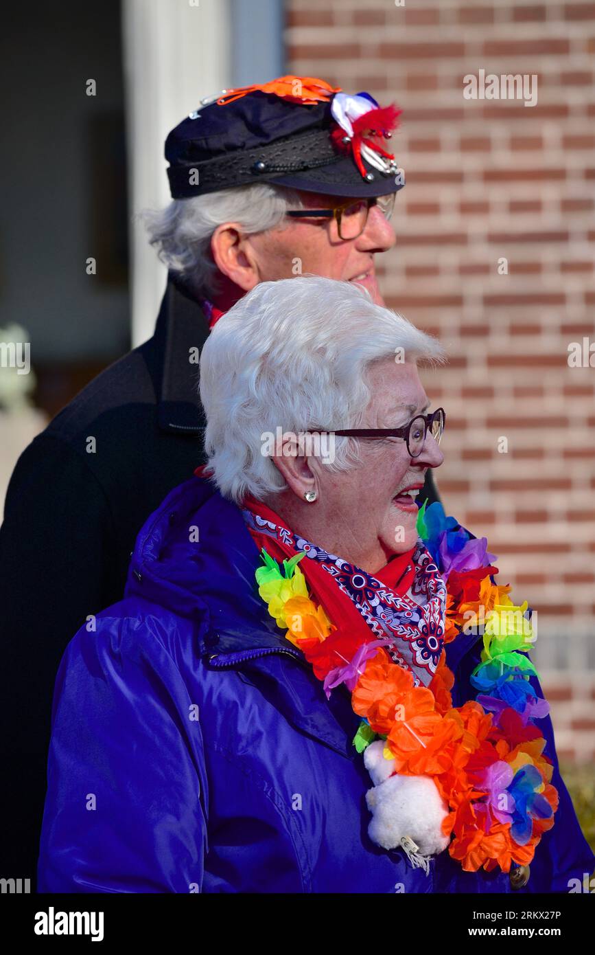 Zuschauer der Karnevalsparade, ein älteres Paar, das mit Karnevalsattributen geschmückt ist, freuen sich auf den nächsten Teilnehmer der Karnevalsparade Stockfoto