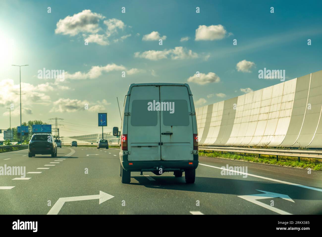 Der Van fährt bei Sonnenuntergang auf der Asphaltstraße durch den schallabsorbierenden Tunnel. Holland Stockfoto