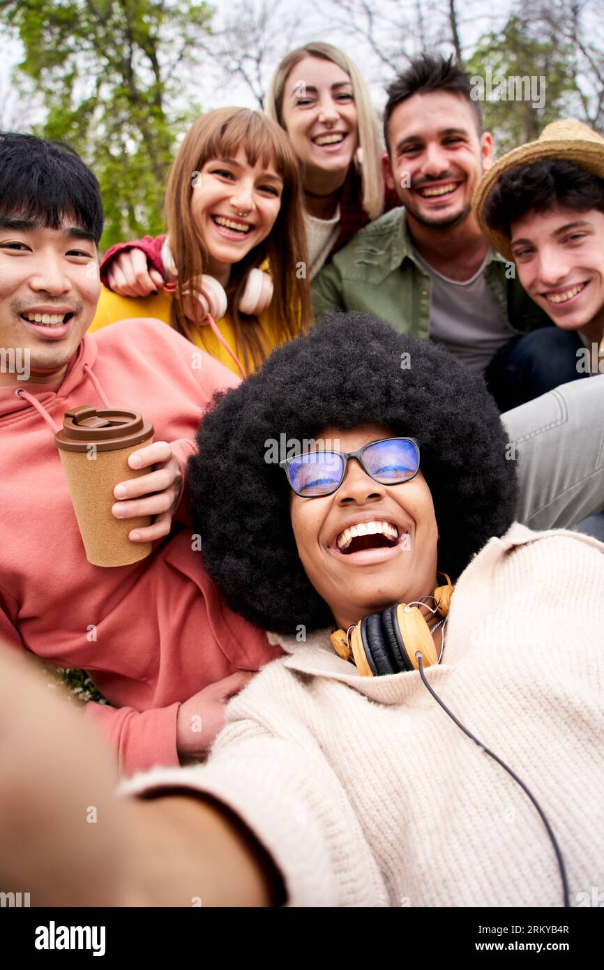 Vertikales glückliches Selfie von jungen Freunden aus mehreren ethnischen Gruppen, die vor der Kamera lachen. Porträt Gen z Stockfoto