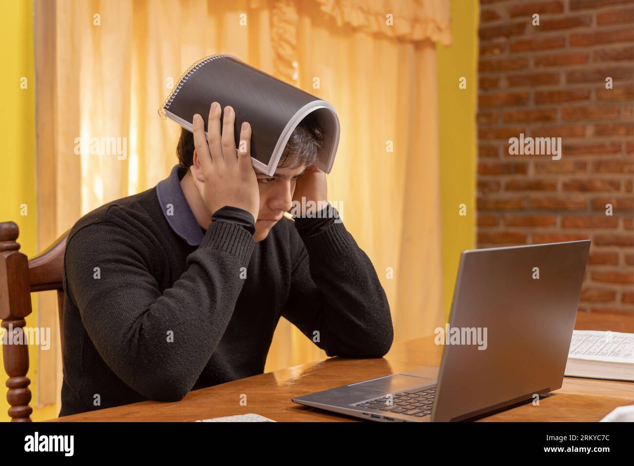 Erschöpfter Schüler, der vor einem Laptop studiert. Stockfoto