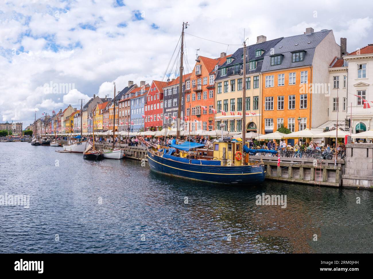 Kopenhagen, Dänemark - 8. August 2023: Der berühmteste Kanal Kopenhagens mit seinen malerischen bunten Häusern mit Blick auf die angelegten Segelboote. Stockfoto