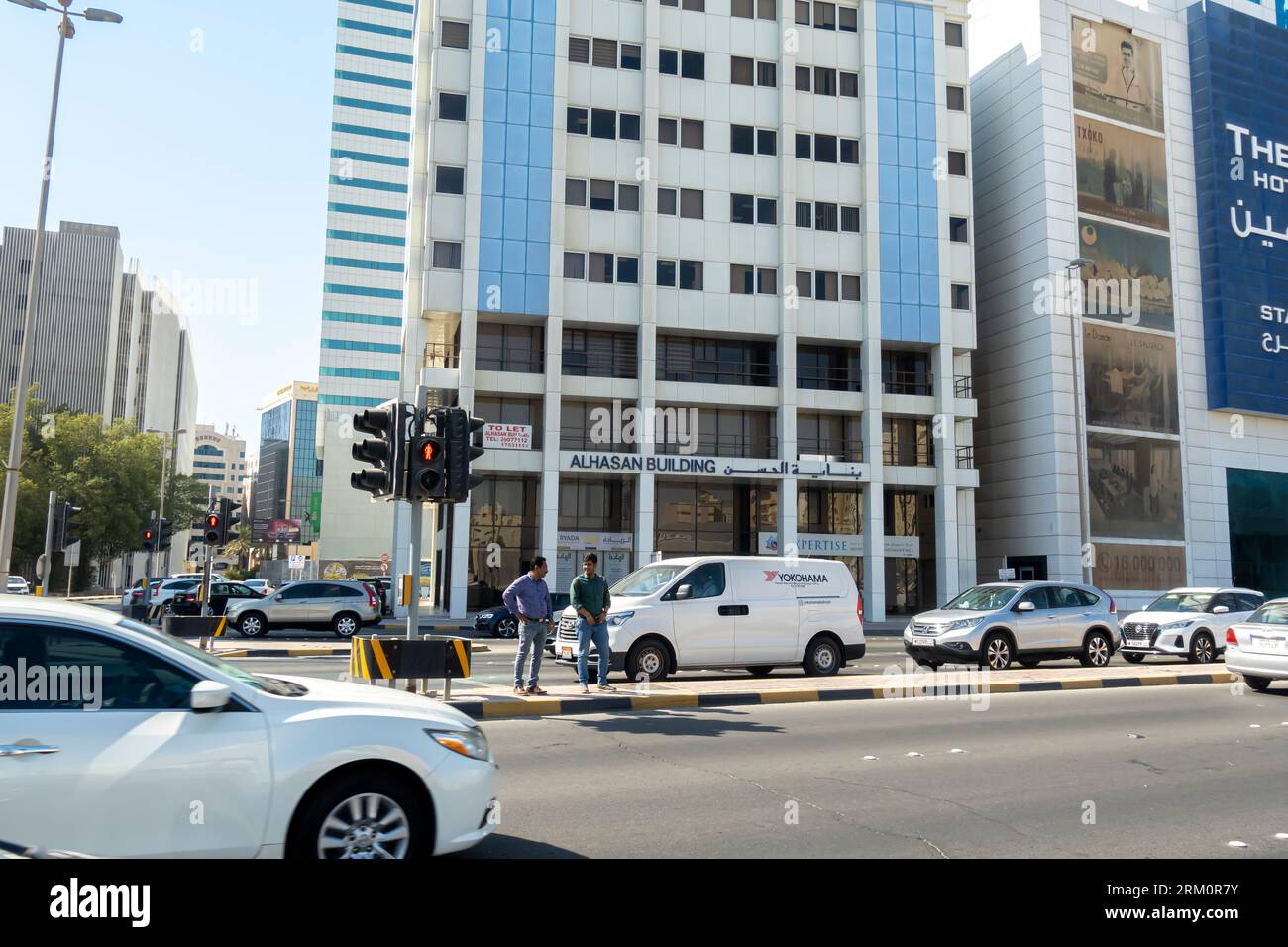 Fußgänger, die auf einem Stoppschild stehen, warten darauf, die befahrene Straße in Manama Bahrain zu überqueren Stockfoto
