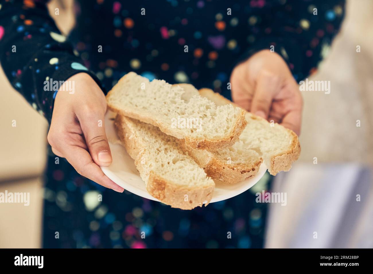 Vollkornbrot auf einem Teller, das Kind hält einen Teller. Frisches Brot aus nächster Nähe. Das Konzept der gesunden Ernährung und der traditionellen Bäckerei. Hochwertige Fotos Stockfoto