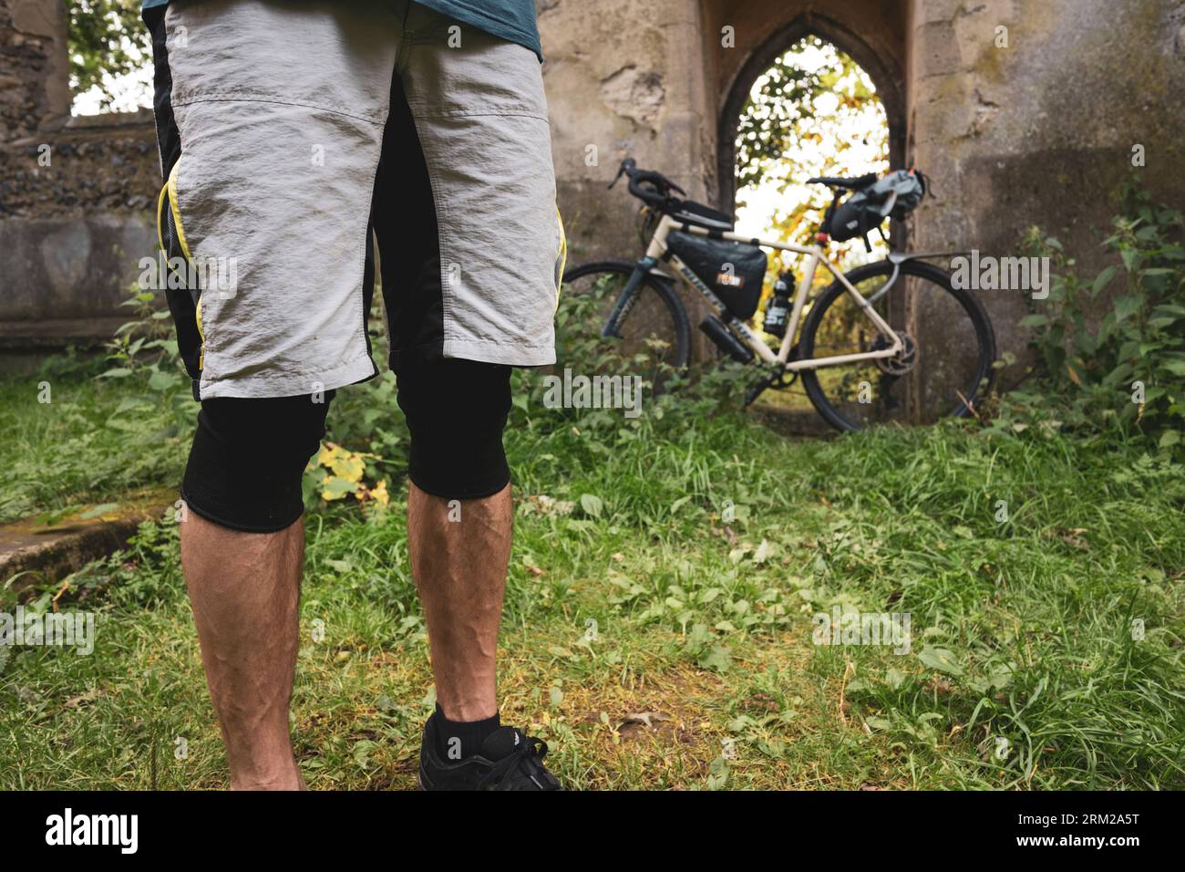 Ein Mann posiert auf seinem Fahrrad in der alten Ruine der St Margarets Church in Norfolk England Stockfoto