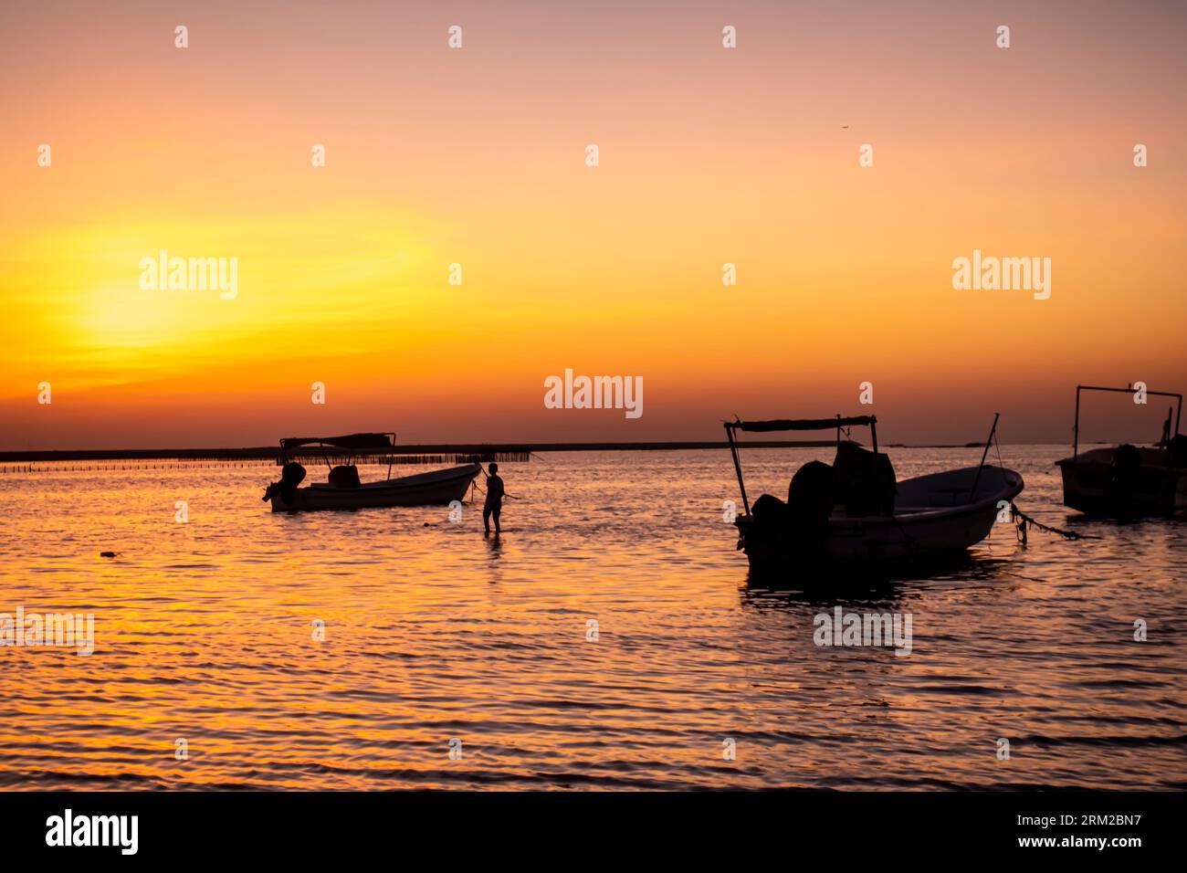 Fischerboote bei Sonnenuntergang am Strand von Karbabad, Seef Beach Bahrain Stockfoto