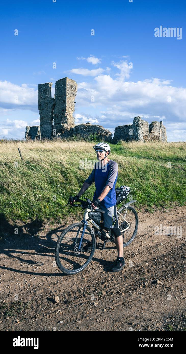 Ein Mann auf einer Fahrradtour fährt an der alten Ruine der Church of St James in der Nähe von Kings Lynn in Norfolk England vorbei Stockfoto