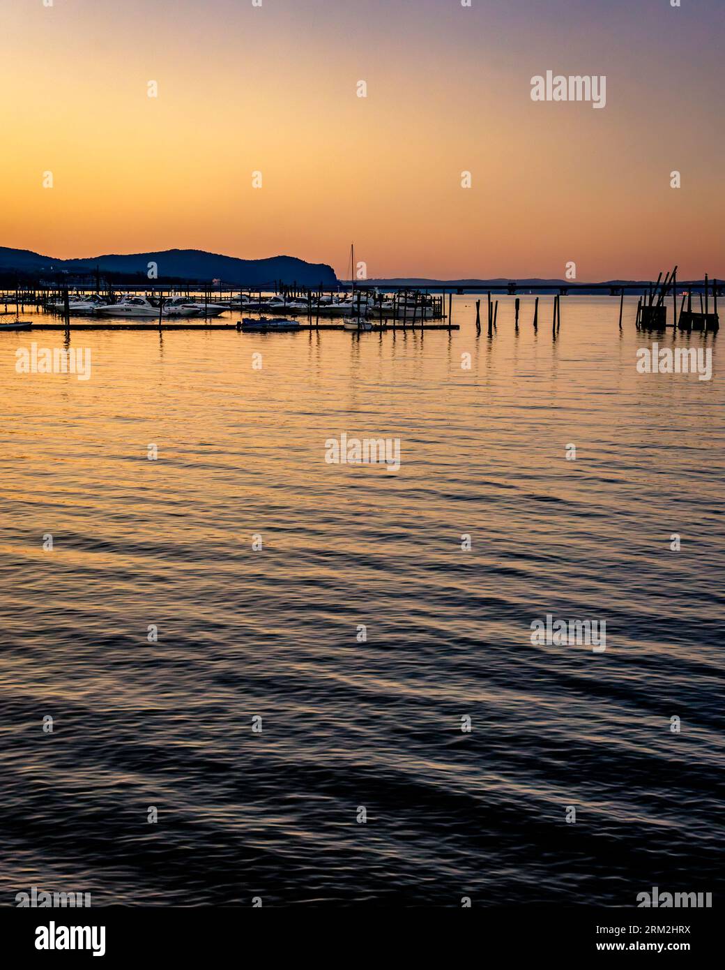 Piermont, NY - US - 20. August 2023 vertikaler Blick auf einen Sonnenuntergang über dem Hudson River und Piermonts Yachthäfen mit Reflexionen. Stockfoto