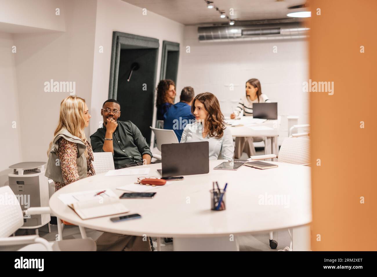 Multirassische, generationenübergreifende Kollegen lernen gemeinsam im modernen Klassenzimmer, diskutieren Arbeit, teilen Wissen und Ideen. Stockfoto