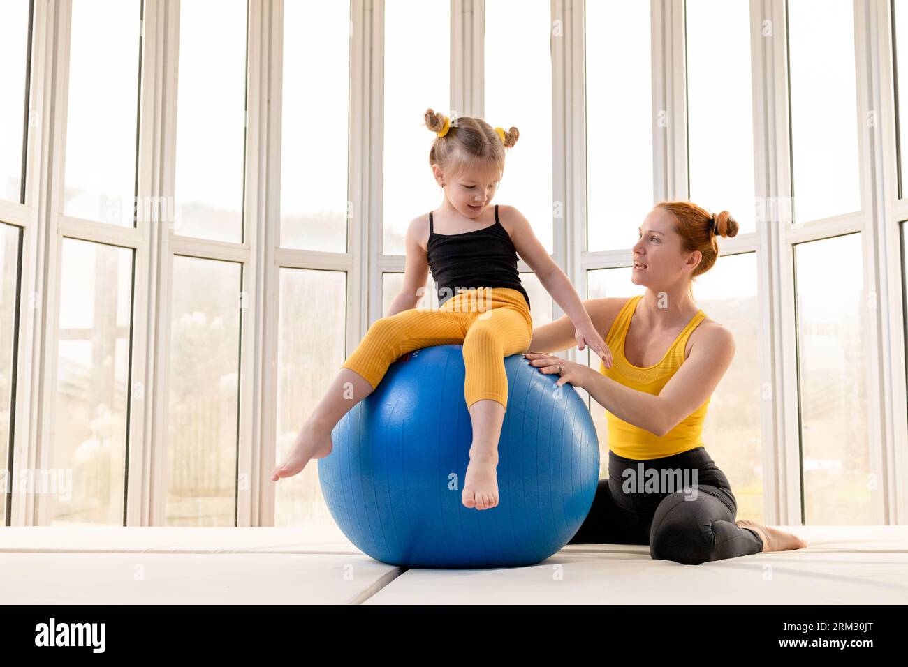 Junge fit Mutter und ihre Tochter Spaß mit Fitness-Ball in einem Fitnessstudio Stockfoto