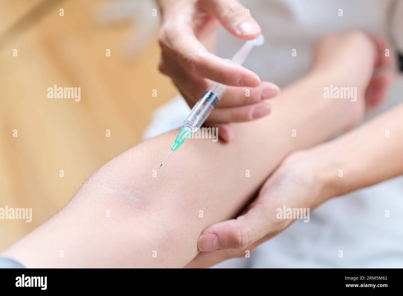 Asiatischer Arzt, der eine Injektion in seinen Arm macht Stockfoto