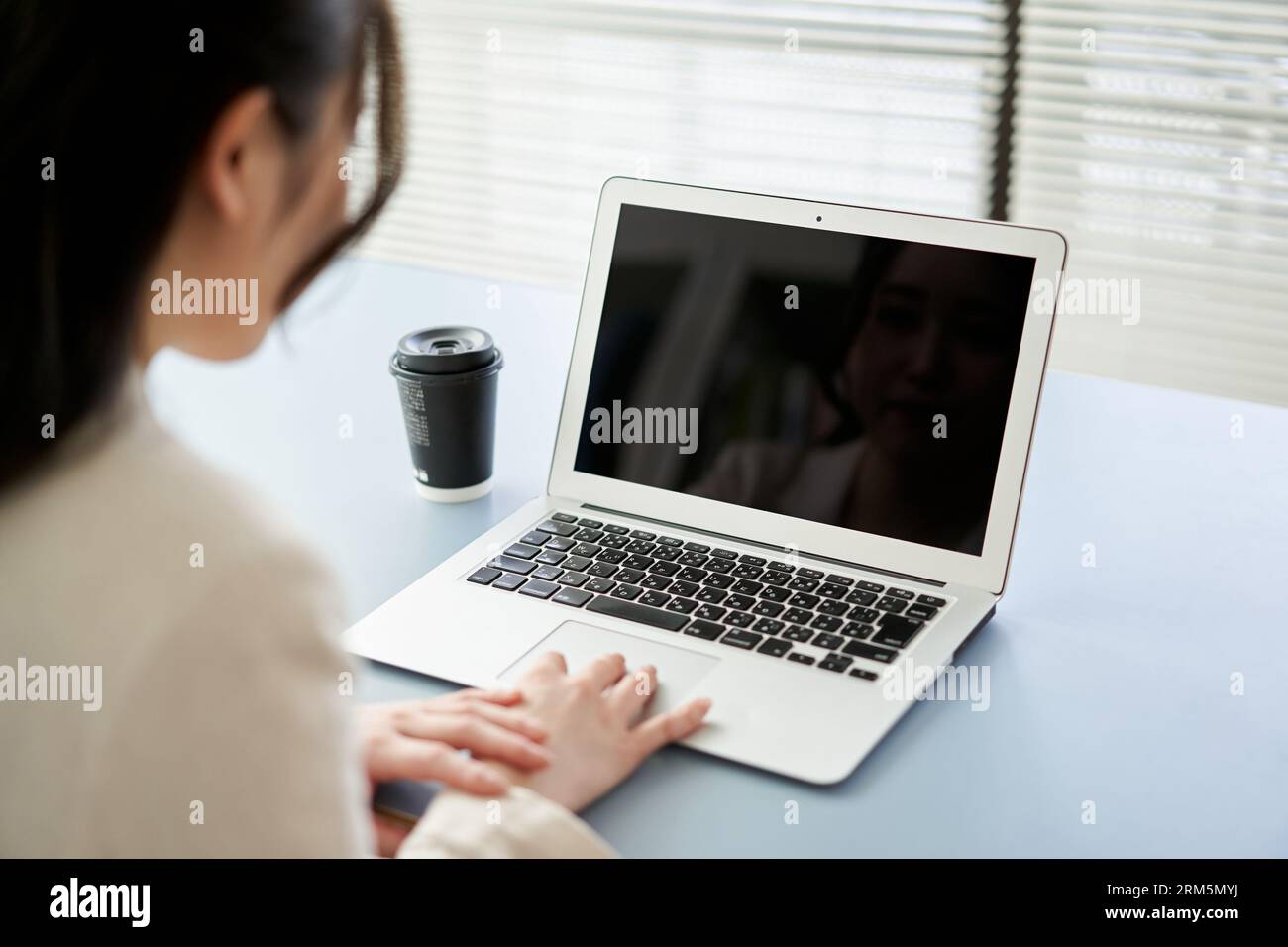 Asiatische Frau, die einen Laptop bedient Stockfoto