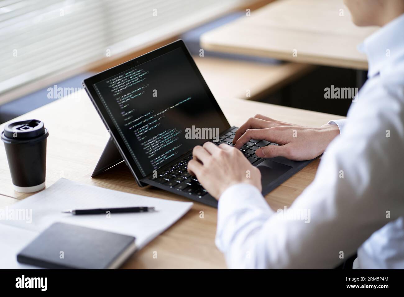 Asiatischer Programmierer, der Code auf einem Laptop schreibt Stockfoto