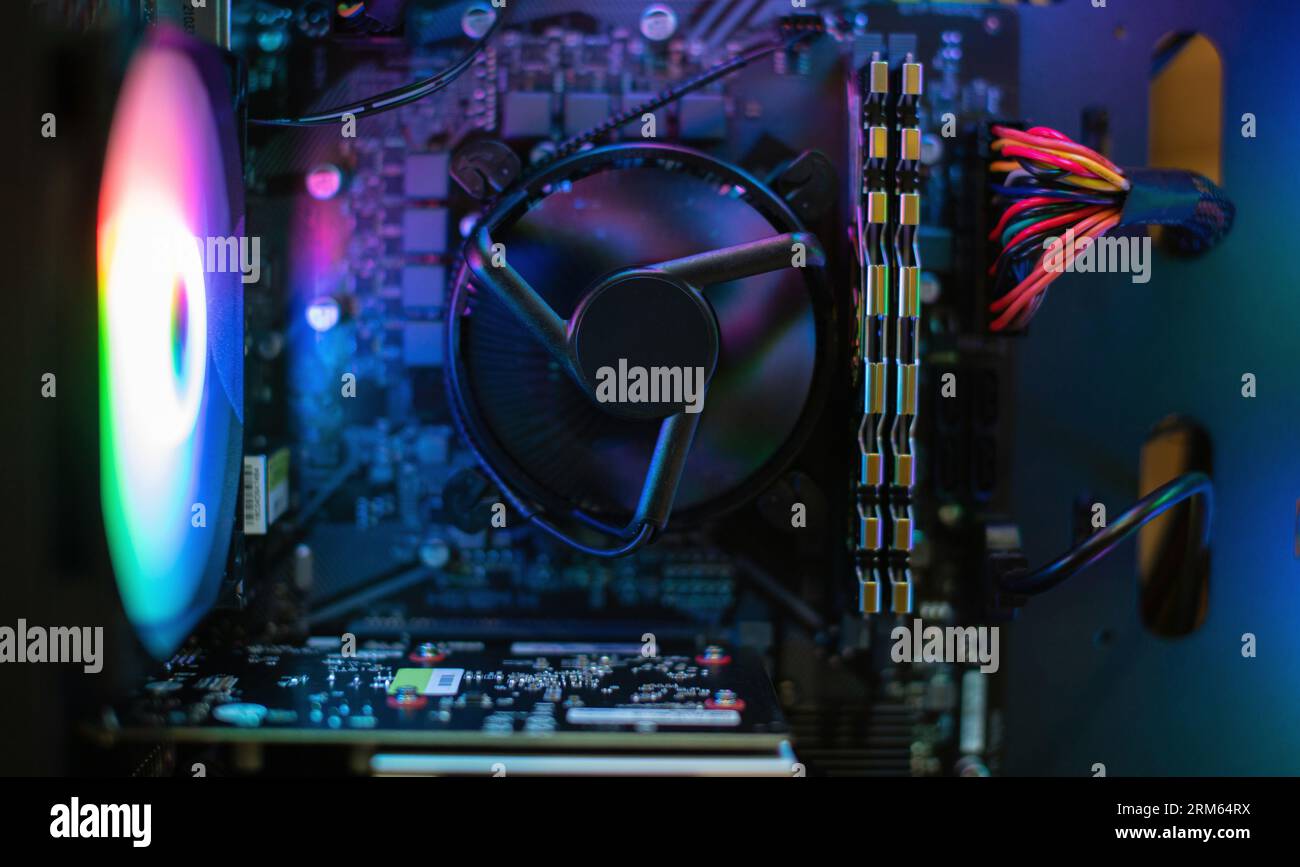 Im Inneren des Computers installierte Grafikkarte Video auf der Hauptplatine/dem blau leuchtenden Lüfter der Hauptplatine Stockfoto