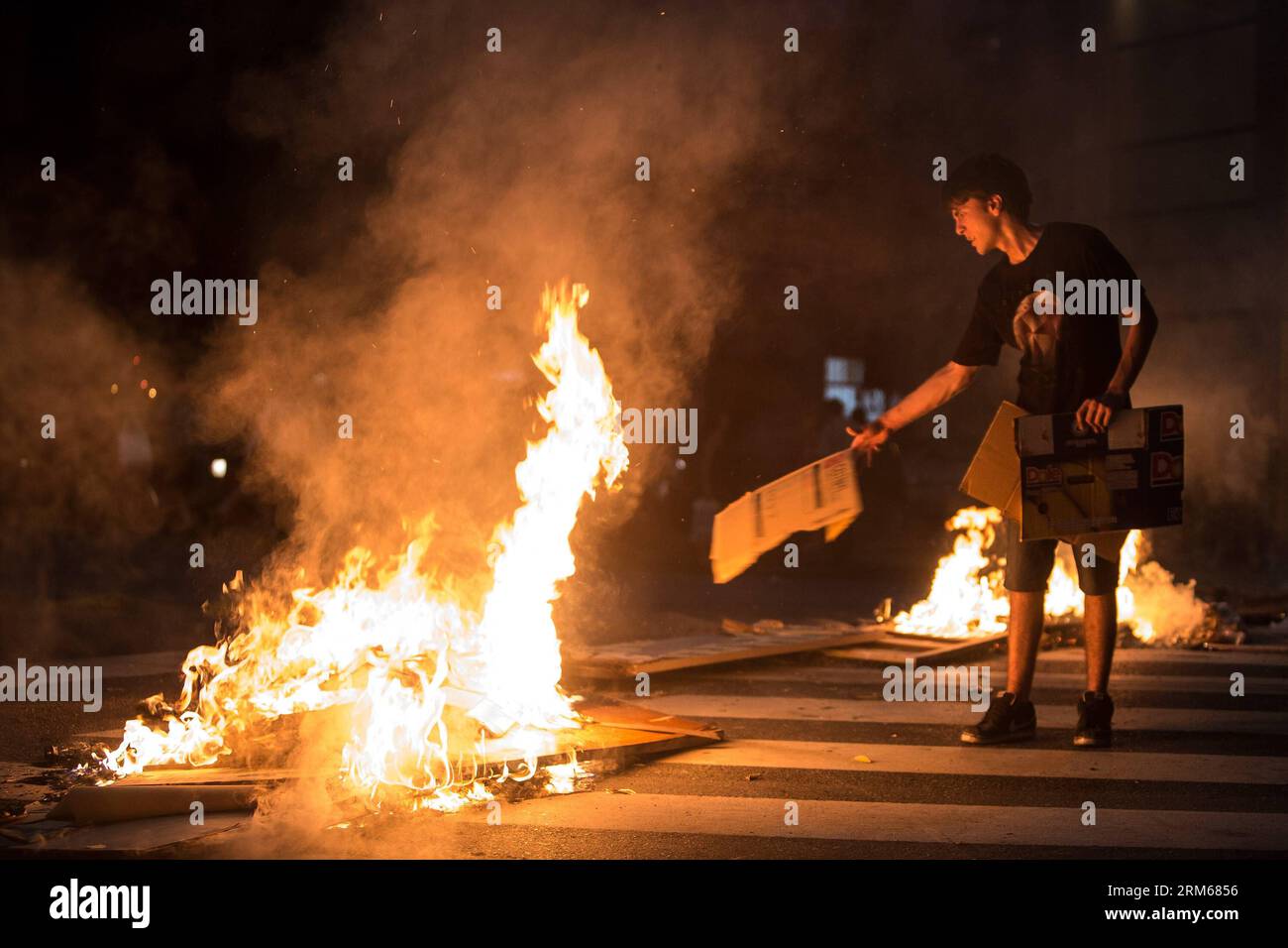 BUENOS AIRES, 17. Dezember 2013 - Ein Bewohner wirft bei einem Protest, der die Rückgabe des Elektrodienstes in Buenos Aires, Argentinien, am 17. Dezember 2013 fordert, Kartonagen in Brand. Aufgrund der hohen Temperaturen, die registriert wurden, versagte die elektrische Anlage in mehreren Stadtteilen von Buenos Aires und seiner Umgebung. Laut lokalen Presseberichten haben die Behörden beschlossen, sie in einigen der von einer Übernachfrage betroffenen Gebiete vorübergehend auszusetzen. (Xinhua/Martin Zabala) (rt) (sp) ARGENTINIEN-BUENOS AIRES-PROTEST PUBLICATIONxNOTxINxCHN Buenos Aires DEZ 17 2013 ein Bewohner wirft Karten-Boards zu einem Feuer während Stockfoto