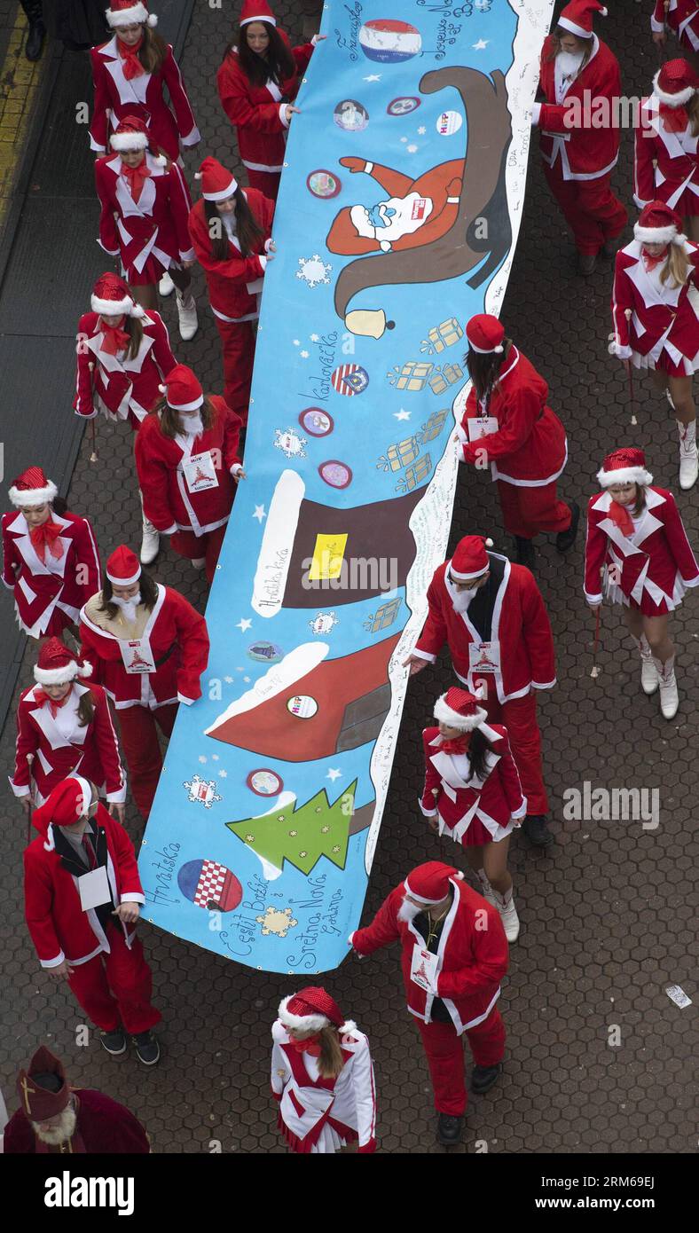 Junge Menschen, die als Weihnachtsmann gekleidet sind, tragen eine hundert Meter lange Weihnachtskarte durch die Innenstadt von Zagreb, Kroatien, am 21. Dezember 2013. Die riesige Weihnachtskarte mit den besten Wünschen der Menschen in Kroatien wird auf einer Weihnachtsmesse in Straßburg, Frankreich, ausgestellt. (Xinhua/Miso Lisanin)(yt) KROATIEN-ZAGREB-RIESIGE WEIHNACHTSKARTE PUBLICATIONxNOTxINxCHN Junge Prominente, die als Weihnachtsmann verkleidet sind, tragen eine 100 Meter lange Weihnachtskarte durch die Innenstadt von Zagreb Kroatien 21. Dezember 2013 die große Weihnachtskarte mit den besten Wünschen der Prominenten Kroatiens wird IN A C ausgestellt Stockfoto