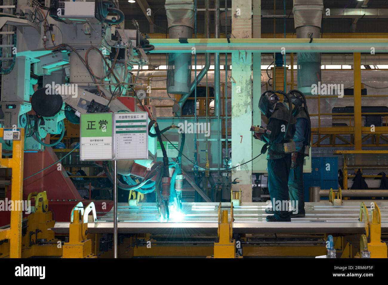 (140109) -- PEKING, 9. Januar 2014 (Xinhua) -- Arbeiter manipulieren Roboter, die die Platte für den Körper eines Hochgeschwindigkeitszuges CRH380A in der Produktionsanlage von Qingdao Sifang Co. Schneiden Ltd., in Qingdao, ostchinesische Provinz Shandong, 3. Januar 2014. Mit der höchsten Geschwindigkeit von 380 km/h ist das Modell der CRH380A der schnellste derzeit in Betrieb befindliche Zug der Welt. Der Zug CRH380A unterscheidet sich von relevanten Fremdprodukten in vier Hauptaspekten: Außenform der Lokomotive, Drehgestell, Karosseriedichtung sowie Netzsteuerungs- und Schleppsysteme. Es wurde nach internationalen Standards und in einigen Fällen entworfen Stockfoto