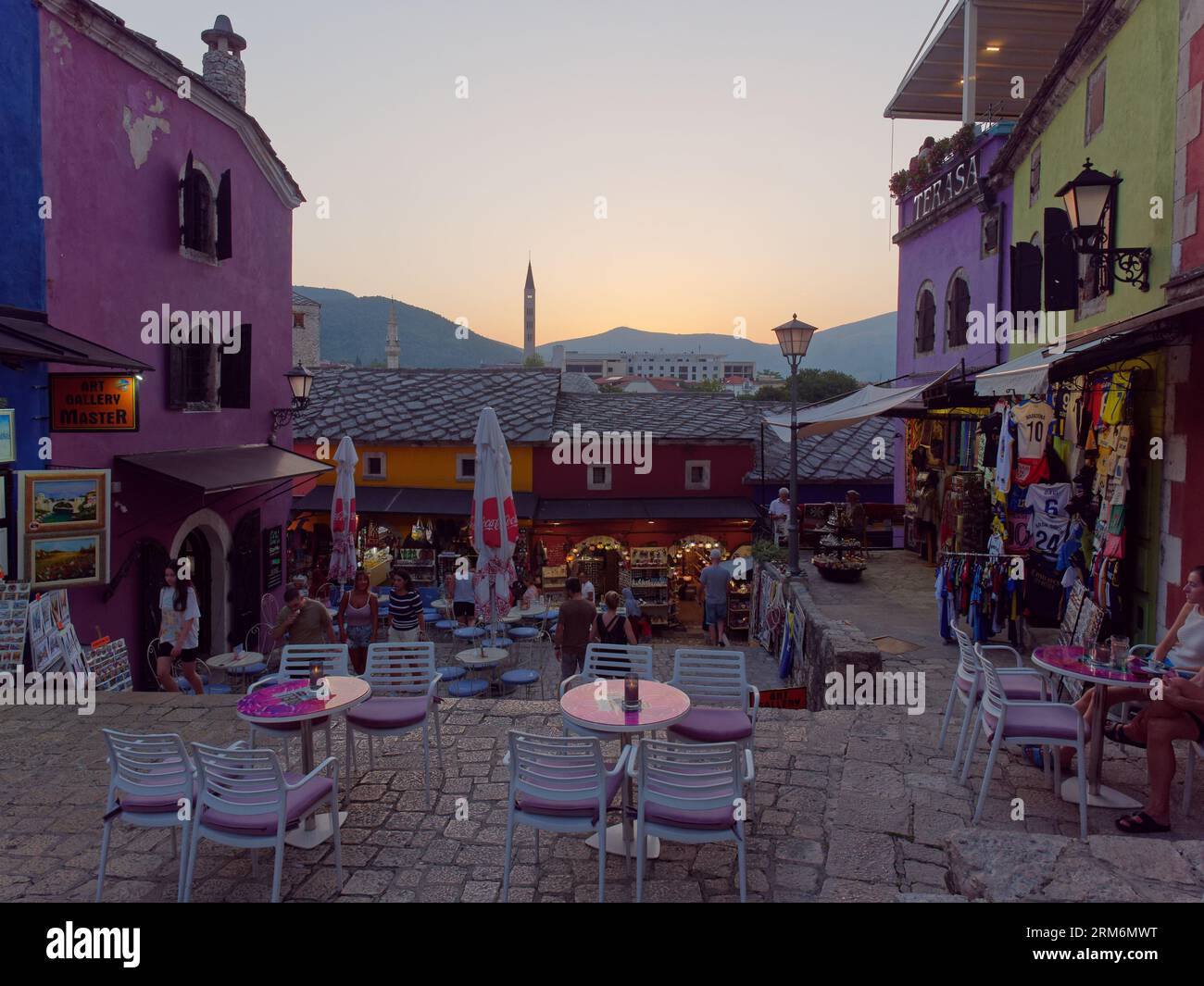Menschen vor einem Café in der farbenfrohen Altstadt von Mostar und UNESCO-Weltkulturerbe an einem Sommerabend, der sich dem Sonnenuntergang nähert. Bosnien und Herzegowina, 26. August 2023. Stockfoto