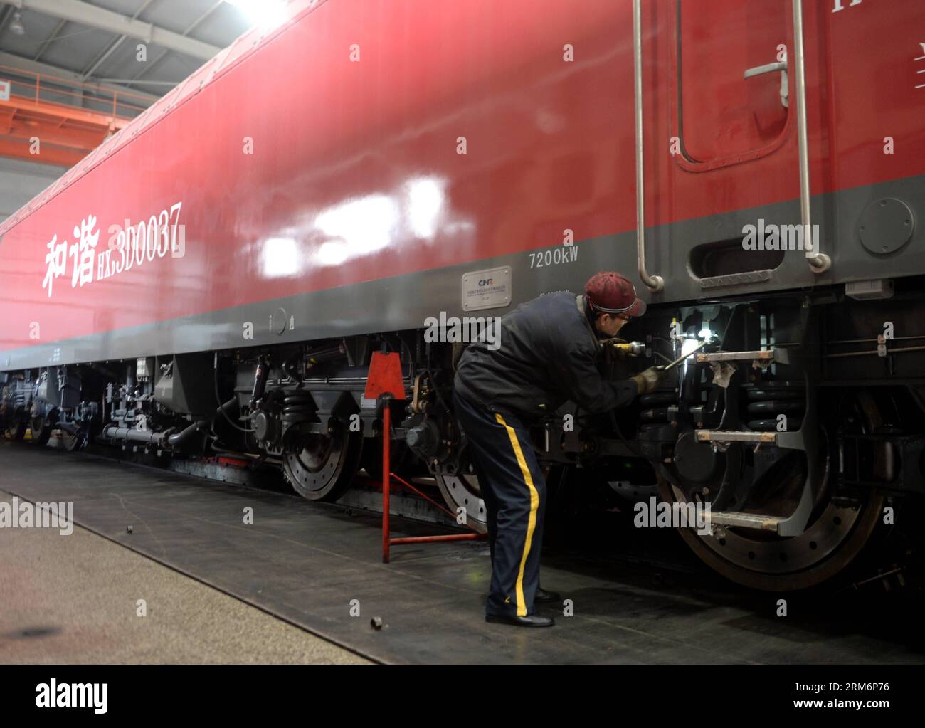 (140124) -- LANZHOU, 24. Januar 2014 (Xinhua) -- Ein Mitarbeiter des Eisenbahnbüros Lanzhou untersucht eine Hexie 3D-Elektrolokomotive, bevor sie in Lanzhou, der Hauptstadt der nordwestchinesischen Provinz Gansu, am 24. Januar 2014 eingesetzt wird. Die Hexie 3D-Elektrolokomotive kann 3.000 Passagiere mit einer Höchstgeschwindigkeit von 160 km/h befördern. Es ist das neueste Modell der Elektrolokomotiven der Hexie-Klasse. Dalian Locomotive and Rolling Stock Co., Ltd Die CNR Group, der Hersteller, hat bereits 40 Hexie 3D-Lokomotiven für das Eisenbahnsystem zur Verfügung gestellt, die während der Chunyun, einer 40-tägigen Spring Festival trave, eingesetzt werden Stockfoto