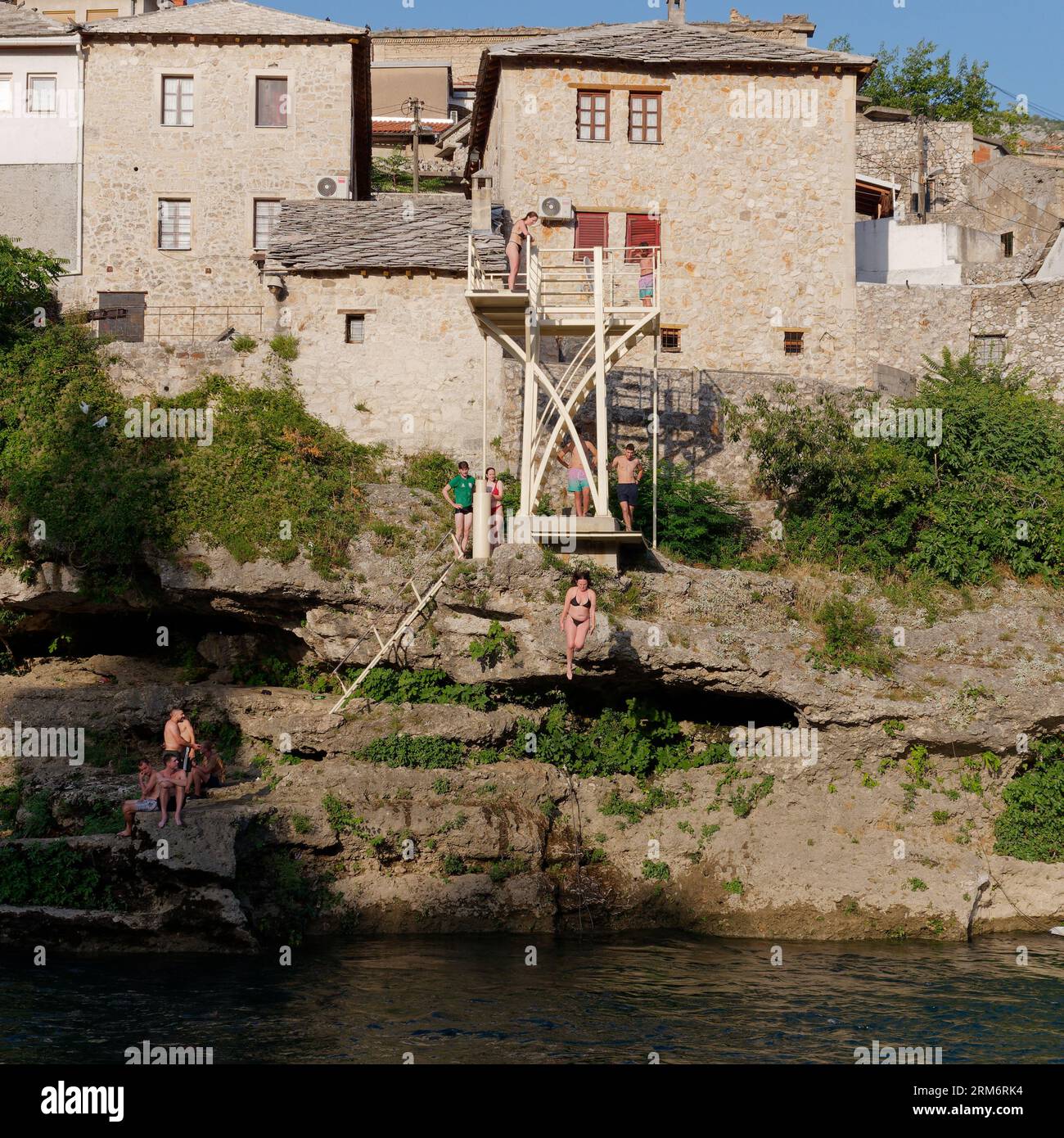 Menschen, die von einer Tauchtrainingsplattform über den Neretva River in Mostar, Bosnien und Herzegowina, springen, 25. August 2023. Stockfoto