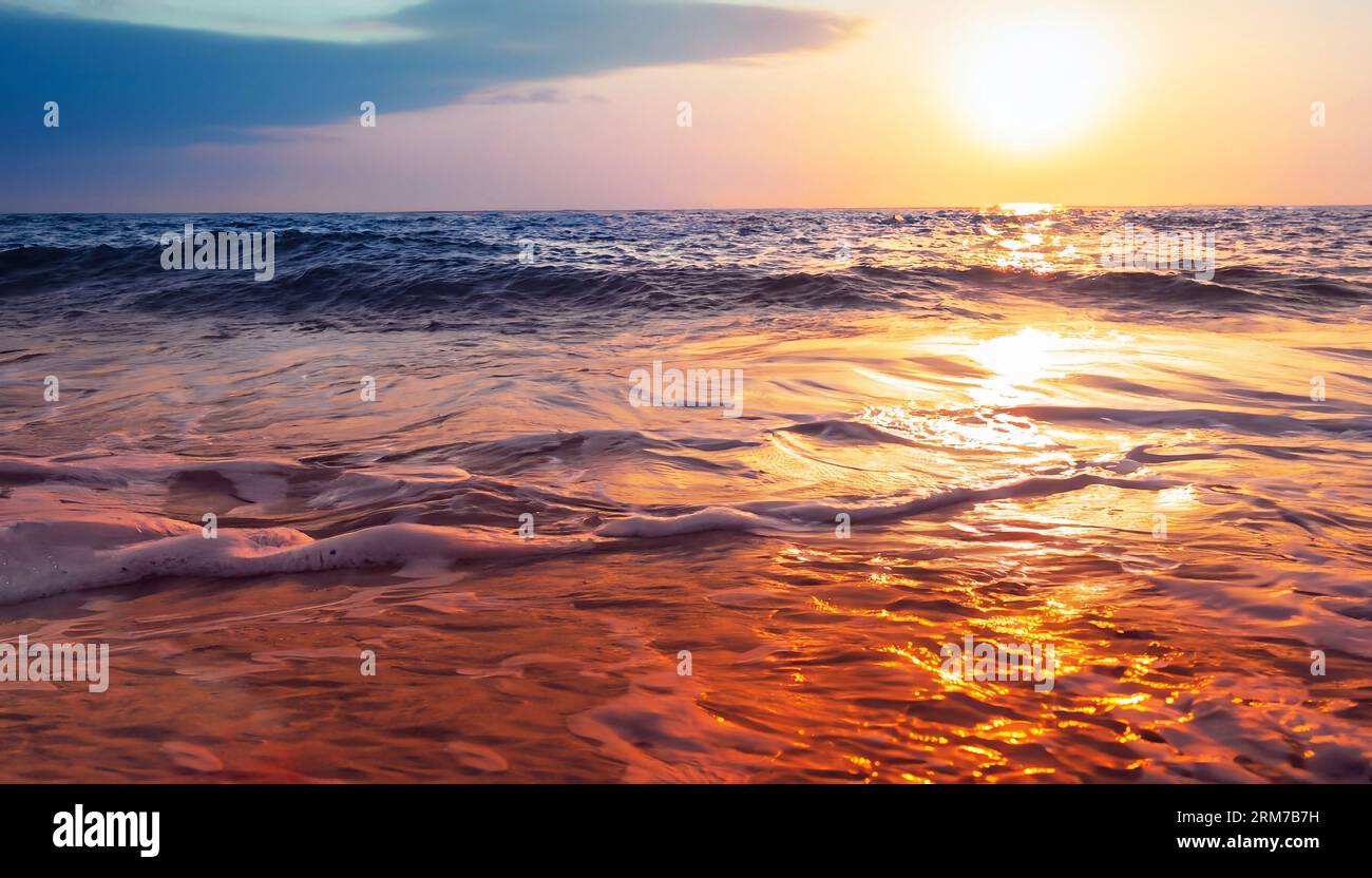 Majestätischer Blick aus der Nähe auf ruhige Meereswellen mit orangefarbenem Sonnenaufgang und Sonnenlicht. Tropische Inselstrandlandschaft, exotische Küste. Sommerurlaub Stockfoto