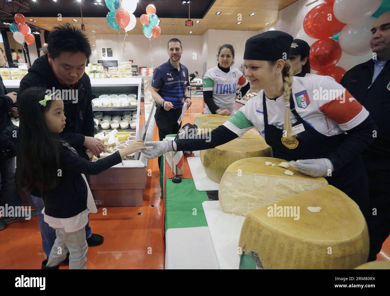 Ein Mitarbeiter teilt einem jungen Mädchen in einem Supermarkt in Vancouver, Kanada, am 22. März 2014 ein Stück Parmigiano-Reggiano-Käse. Mehr als 360 Läden in Kanada versuchen gemeinsam, den Guinness World Records-Titel für die meisten Parmigiano-Reggiano-Käseräder zu brechen, die gleichzeitig gerissen werden. Der aktuelle Weltrekord liegt bei 426 Rädern, die 2013 erreicht wurden. Parmigiano-Reggiano ist der König des Käses, der in Italien nach dem gleichen Rezept seit fast 1.000 Jahren hergestellt wird. (Xinhua/Liang Sen) CANADA-VANCOUVER-CHEESE-CRACKING PUBLICATIONxNOTxINxCHN A Staff teilt ein Stück o Stockfoto