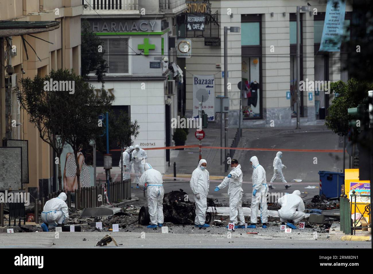 ATHEN, Polizei-Bombenbeseitigungsexperten suchen nach Beweisen in der Nähe von Überresten eines Autos nach einer Autobombenexplosion im Zentrum von Athen, Griechenland, am 10. April 2014. Eine Autobombe explodierte am frühen Donnerstag vor der griechischen Zentralbank im Zentrum von Athen und verursachte Schäden an Büros, Geschäften und Autos in der Nähe. Es wurden keine Verletzungen gemeldet. Der Vorfall ereignete sich zu einer Zeit, als Griechenland am Donnerstag zum ersten Mal seit Beginn der Krise im Jahr 2010 seine Rückkehr an die internationalen Anleihemärkte machen sollte, indem es den Anlegern fünfjährige Anleihen anbot. (Xinhua/Marios Lolos) (lyx) GRIECHENLAND-ATHEN-CAR BOMB-BLAST Stockfoto