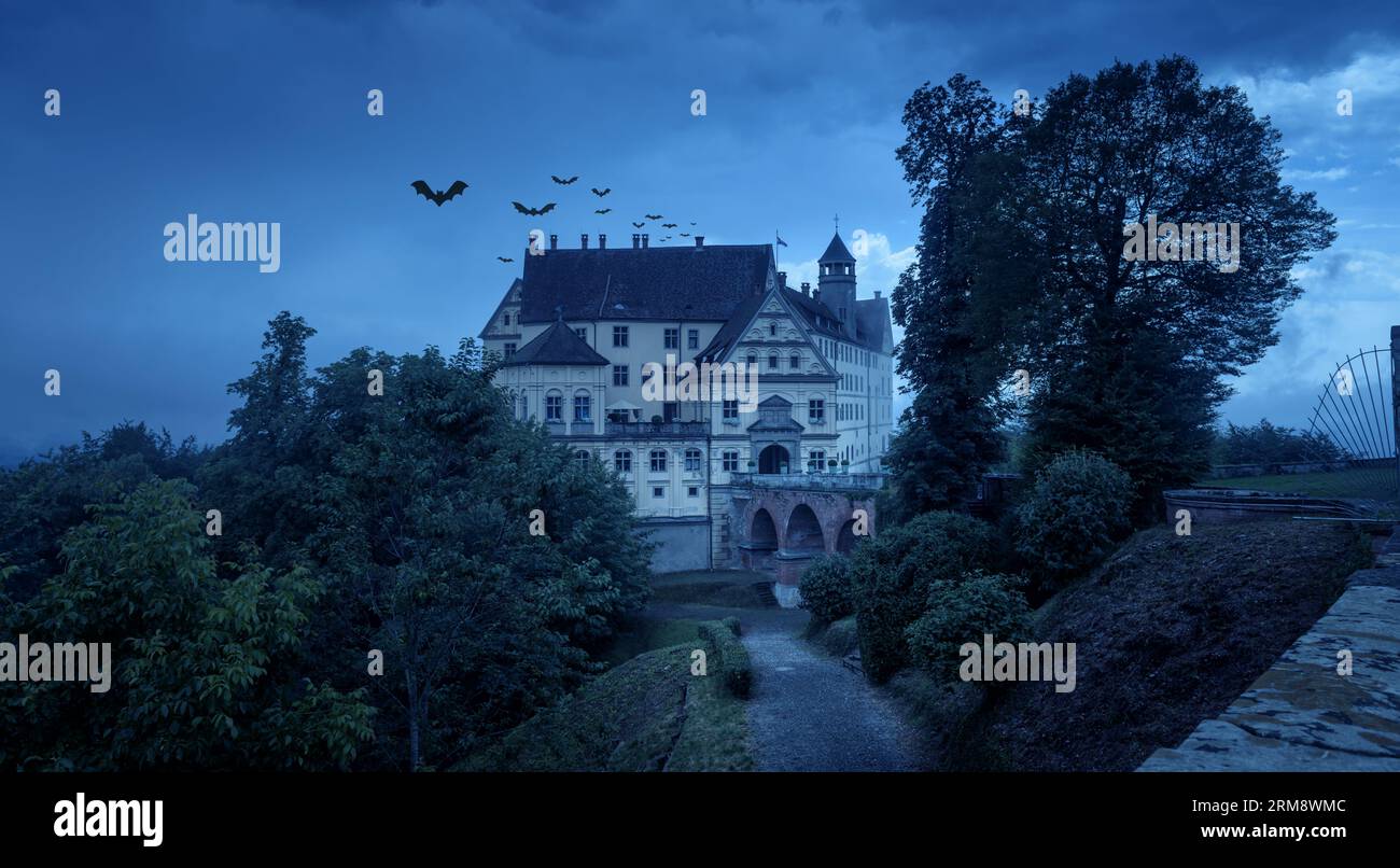 Spukschloss in der Halloween-Nacht, altes gruseliges Herrenhaus mit Fledermäusen in der Abenddämmerung. Blick auf die gruselige dunkle Burg in der blauen Dämmerung. Düstere Szene zum Thema Hallowen. Stockfoto