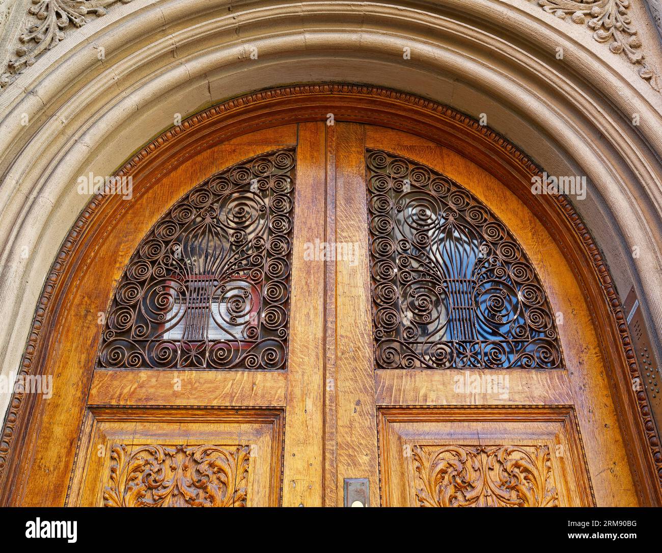 Upper West Side: Geschnitzte Holztüren mit aufwändigen Metall- und Glaseinsätzen werden von einem Kalksteinbogen an der 358 West End Avenue, einem Wahrzeichen des Stadthauses, eingerahmt. Stockfoto