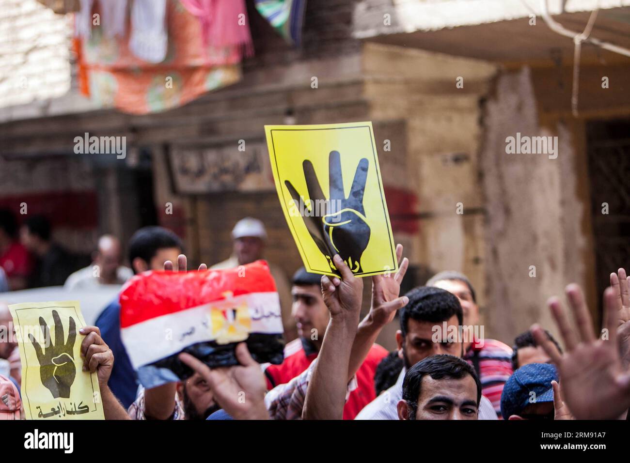 Anti-Militär-Demonstranten heben Banner auf und drücken den vier-Finger-Gruß während einer Demonstration im Al-Matareya-Viertel in Kairo, Ägypten, im Mai. 2, 2014. Antimilitärische Demonstranten hielten im ganzen Land Kundgebungen ab, um die Rückkehr des vertriebenen Präsidenten Mohamed Mursi zu fordern. (Xinhua/Amru Salahuddien) ÄGYPTEN-KAIRO-KUNDGEBUNG PUBLICATIONxNOTxINxCHN Anti-Militär-Demonstranten heben Banner und gesten die vier Finger Salute während einer Demonstration im Al Matareya-Viertel in Kairo Ägypten 2. Mai 2014 Anti-Militär-Demonstranten Hero Kundgebungen im ganzen Land, um die Rückkehr des abgesetzten Präsidenten Moha zu fordern Stockfoto