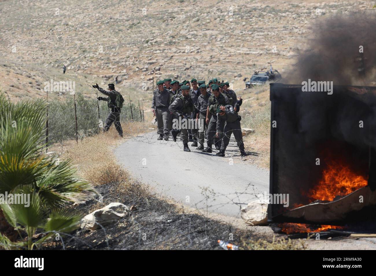 JERUSALEM, 14. Mai 2014 - israelische Polizisten werden mit Barrikaden blockiert, als sie am 14. Mai 2014 zum Abbau illegaler Gebäude in der Siedlung Maale-Rechavam nördlich von Hebron marschieren. Israelische Verteidigungskräfte (IDF) und Polizeikräfte zerstörten am Mittwoch acht illegale Gebäude in der Siedlung Maale-Rechavam nördlich von Hebron. Die israelische Regierung erklärte diese Gebäude im Westjordanland, die auf privatem palästinensischem Land errichtet wurden, für illegal und müssen abgetragen werden. Die Siedler wehrten sich mit Barrikaden und brennenden Reifen am Eingang der Siedlung als Armee Stockfoto