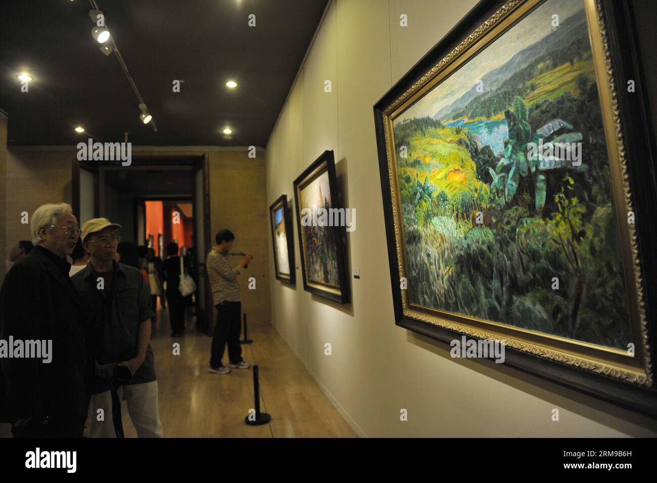 (140516) -- PEKING, 16. Mai 2014 (Xinhua) -- Besucher plündern Gemälde des chinesischen Ölmalers Cao Xinlin während seiner Ausstellung Bond to the Loved Land in Beijing, Hauptstadt Chinas, 16. Mai 2014. Über 180 Gemälde, die Cao während seiner fast 60-jährigen Kunstkarriere schuf, waren zu sehen. (Xinhua/Lu Peng) (MP) CHINA-BEIJING-OIL PAINTINGS-EXHIBITION (CN) PUBLICATIONxNOTxINxCHN Peking 16. Mai 2014 XINHUA-Besucher beuten Gemälde des chinesischen Ölmalers Cao während seiner Ausstellung Bond to the loved Country in Beijing Capital of China am 16. Mai 2014 über 180 Gemälde, die Cao schuf Stockfoto