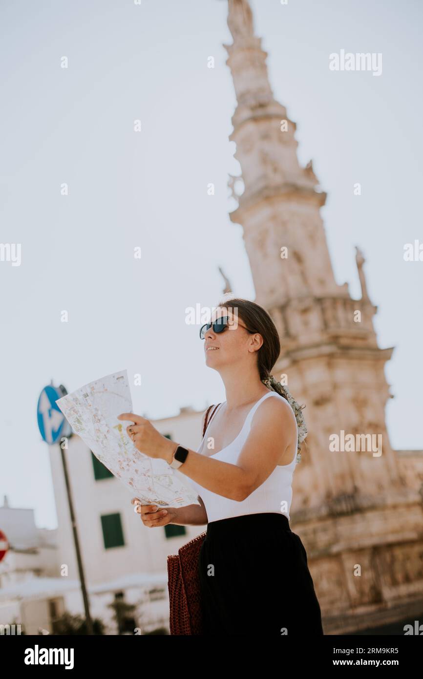 Weibliche Touristen mit einem Stadtplan von der Statue des Heiligen Oronzo in Ostuni, Italien Stockfoto