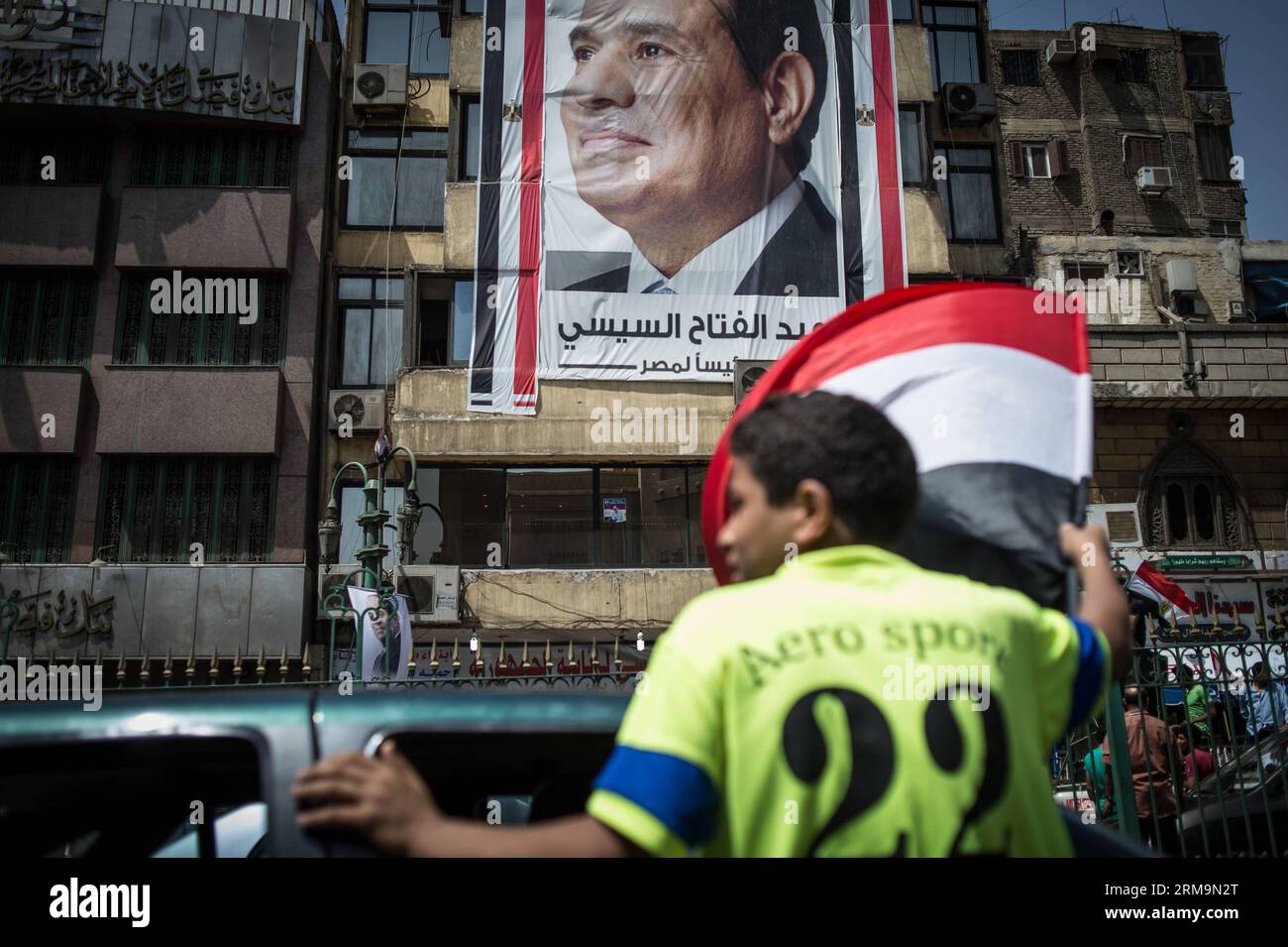 (140527) -- KAIRO, 27. Mai 2014 (Xinhua) -- Menschen feiern vor einem hübschen Plakat von Ägyptens Präsidentschaftskandidat Abdel-Fattah al-Sisi in der Nachbarschaft von Gamalia, das als seine Heimatstadt gilt, im alten Kairo, Ägypten, am 27. Mai 2014. Der Dienstag ist der letzte Tag der zweitägigen Präsidentschaftswahlen, die ersten Wahlen seit dem Sturz des ehemaligen islamistischen Präsidenten Mohamed Mursi im vergangenen Jahr. Ex-Militärchef Abdel-Fattah al-Sisi, der Mursis Sturz führte, ist bereit, einen leichten Sieg über seinen einzigen Rivalen im Rennen zu erzielen, den linken Führer Hamdeen Sabahy, der im Präsidenten von 2012 Dritter wurde Stockfoto