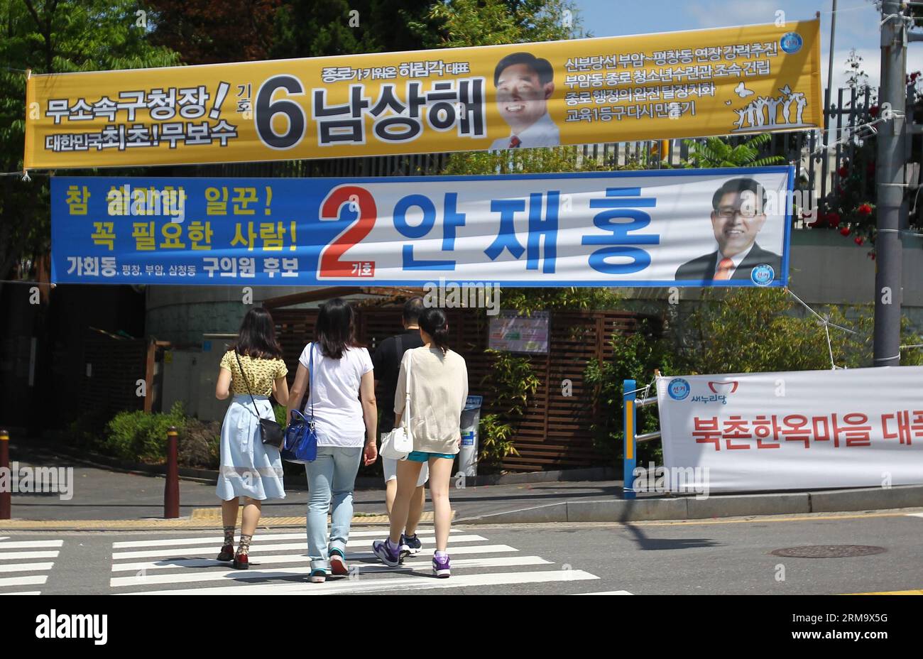 (140604) -- SEOUL, 4. Juni 2014 (Xinhua) -- People Walk Pass Wahlplakate in Seoul, Südkorea, 4. Juni 2014. Die Südkoreaner werden insgesamt 3.952 Beamte wählen, darunter 17 Bürgermeister, Provinzgouverneure und Superintendenten, 226 Leiter von Verwaltungseinheiten auf niedriger Ebene sowie etwa 3.700 Gemeindemitglieder. Die Abstimmung begann von 6.00 Uhr an 13.665 Wahllokalen landesweit und ging nach Angaben der Nationalen Wahlkommission (NEC) bis 18.00 Uhr weiter. (Xinhua/Yao Qilin)(ctt) SÜDKOREA-SEOUL-WAHLEN PUBLICATIONxNOTxINxCHN Seoul 4. Juni 2014 XINHUA Prominrities Walk Passport Stockfoto