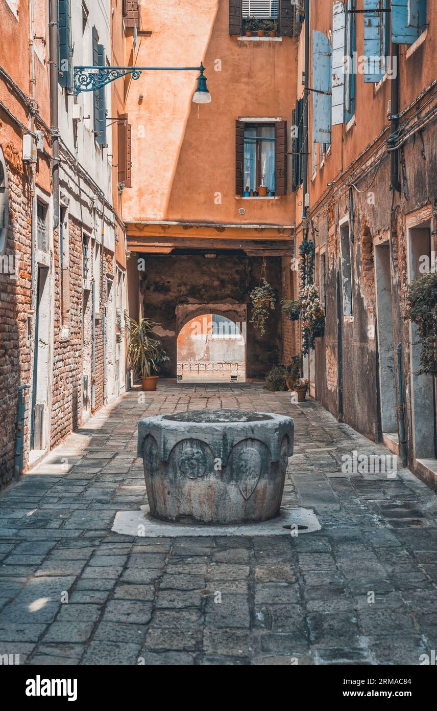 Enge Fußgängerzone mit Kopfsteinpflaster in Venedig, Italien. Alte, verschlissene mittelalterliche Gebäude. Stockfoto