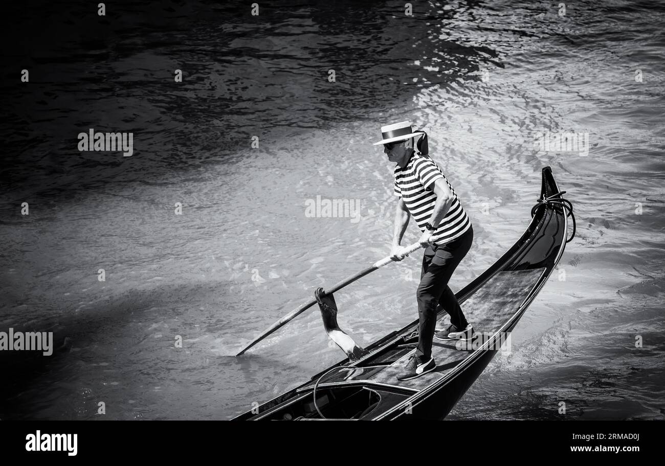 Venedig, Italien - Mai 2023: Ein Gondoliere oder venezianischer Bootsmann fährt eine Gondel auf dem Canale Grande in Venedig. Schwarzweißfotografie. Stockfoto