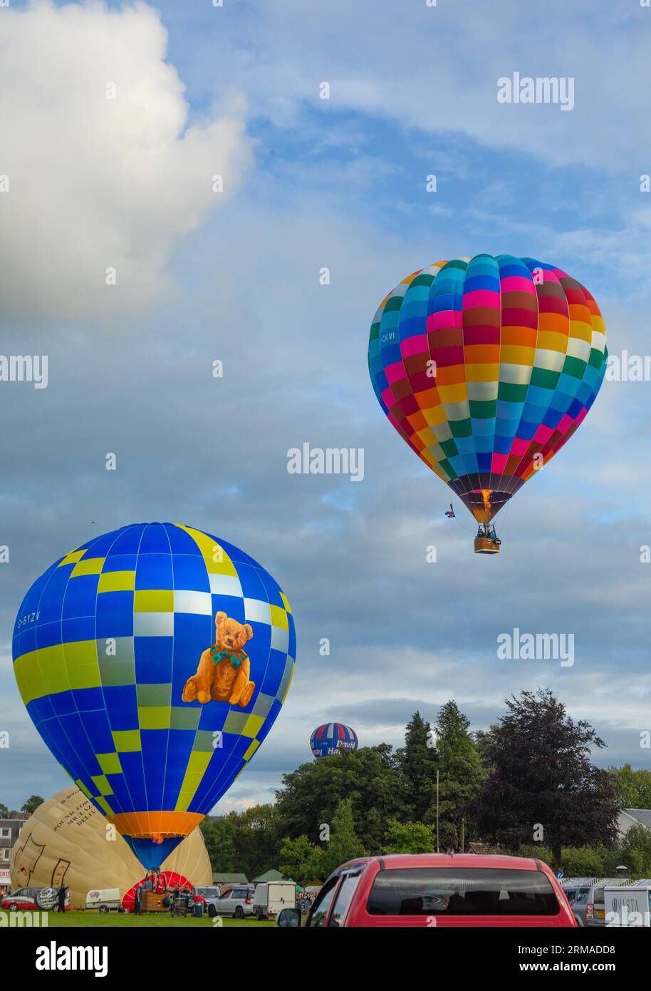 Hot-air balloons taking off, flying and and others being inflated, during the Strathaven Balloon Festival 2023 in Strathaven, Scotland. Stockfoto