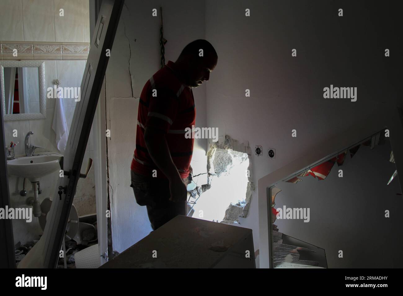 (140703) -- SDEROT (ISRAEL), 3. Juli 2014 (Xinhua) -- ein israelischer Mann inspiziert die Schäden eines Hauses nach einem Projektilangriff von Militanten aus Gaza in Sderot, Israel, am 3. Juli 2014. Früher am Donnerstag trafen drei Geschosse Wohngebäude in der israelischen Stadt Sderot, darunter eine Wohnung, die als private Kindergarten dient. Raketen, die über Nacht abgefeuert wurden, schlugen in einigen Teilen der Stadt den Strom aus. Die meisten anderen Geschosse, die am Donnerstag abgefeuert wurden, trafen offene Bereiche und verursachten keine Verletzungen. Zwei Raketen wurden vom israelischen Verteidigungssystem Iron Dome abgefangen und einige fielen kurz Stockfoto