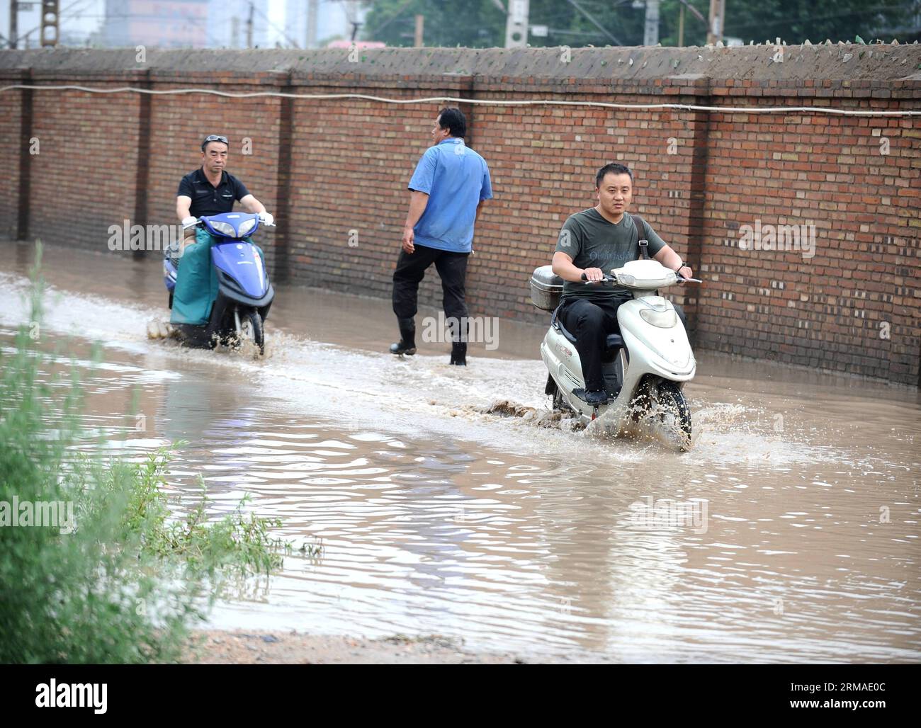 (140704) -- TAIYUAN, July 4, 2014 (Xinhua) -- Pedestrians and motorcyclists travel on a flooded street in Taiyuan, capital of north China s Shanxi Province, July 4, 2014. Rainstorms hit the city on Friday, flooding streets and causing traffic interruptions. (Xinhua/Yan Yan) (mp) CHINA-SHANXI-TAIYUAN-RAINSTORM-FLOODS (CN) PUBLICATIONxNOTxINxCHN Taiyuan July 4 2014 XINHUA pedestrians and Motorcyclists Travel ON a flooded Street in Taiyuan Capital of North China S Shanxi Province July 4 2014 Rainstorm Hit The City ON Friday flooding Streets and causing Traffic interruptions XINHUA Yan Yan MP Ch Stockfoto
