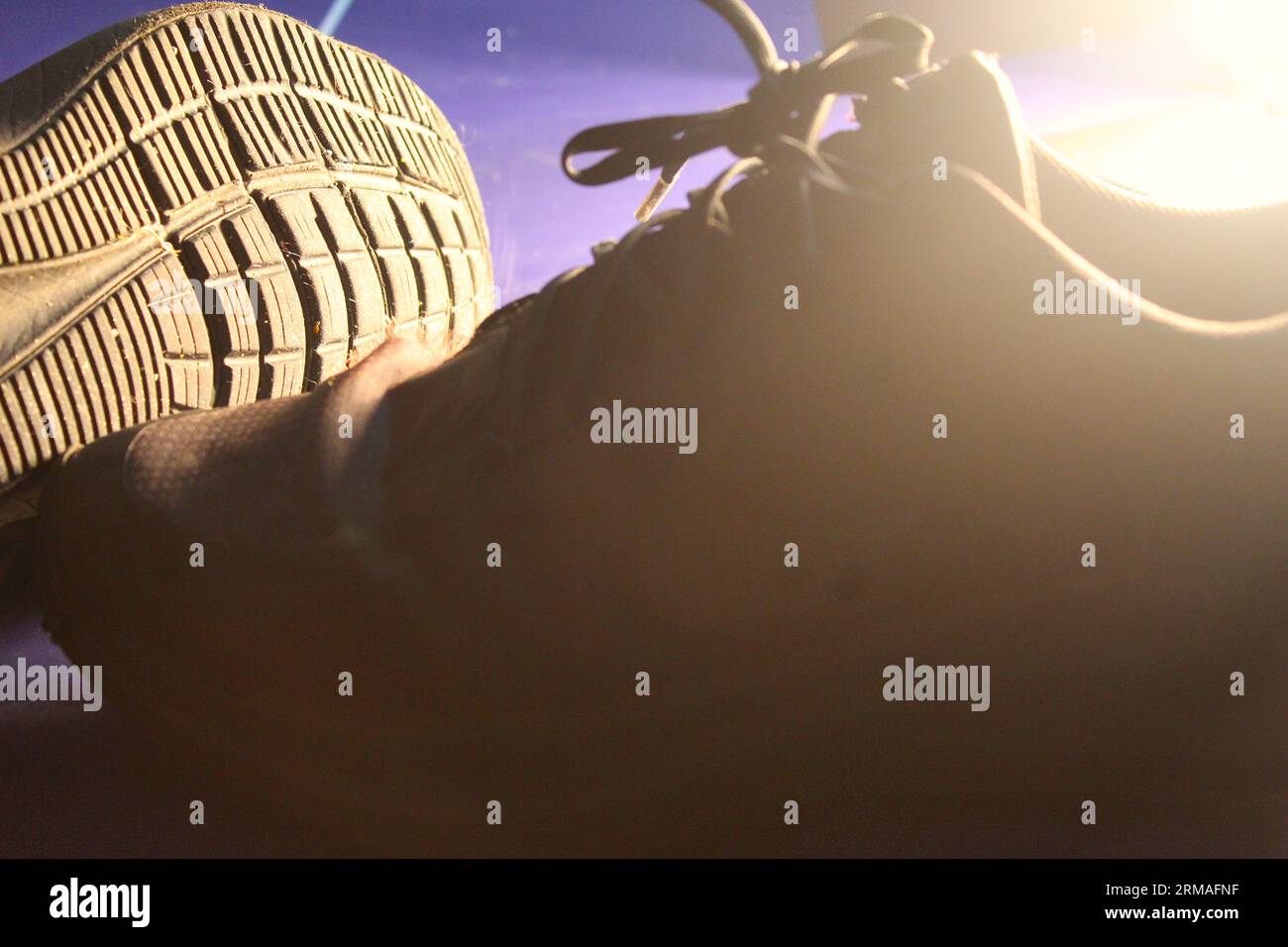 Ein Foto von zwei schwarzen Schuhen nebeneinander auf einem blauen Tisch im Licht. Stockfoto
