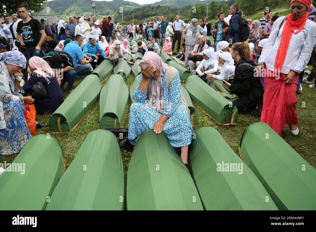 Verwandte, die neben Särgen der Opfer sitzen, trauern vor einer Beerdigung in Potocari, in der Nähe von Srebrenica, Bosnien und Herzegowina, 11. Juli 2014. Die Beerdigung von 175 kürzlich identifizierten Opfern fand hier am Freitag zum Gedenken an den 19. Jahrestag des Massakers von Srebrenica statt. Etwa 7.000 muslimische Männer und Jungen wurden im Juli 1995 von bosnischen serbischen Truppen in Srebrenica und in der Nähe von Srebrenica massakriert, das schlimmste Massaker in Europa seit dem Ende des Zweiten Weltkriegs Xinhua/Haris Memija zjl BIH-SREBRENICA-MASSAKER-19. JAHRESTAG PUBLICATIONxNOTxINxCHN Stockfoto