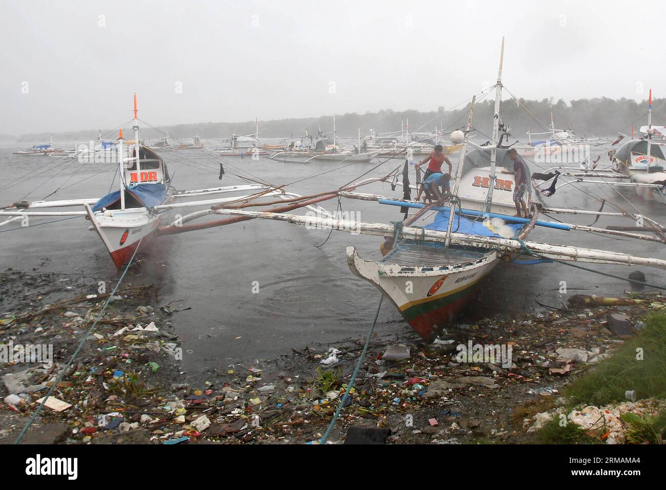 (140716) -- PROVINZ CAVITE, 16. Juli 2014 (Xinhua) -- Fischer versuchen, ihr Boot zu sichern, während sie den starken Winden des Taifuns Rammasun in der Provinz Cavite, Philippinen, am 16. Juli 2014 trotzen. Mindestens 5 Menschen wurden getötet, nachdem der Taifun Rammasun (lokaler Name: Glenda) am Mittwoch die philippinische Hauptstadt Metro Manila lahmlegte. (Xinhua/Rouelle Umali) PHILIPPINEN-CAVITE PROVINZ-TAIFUN RAMMASUN PUBLICATIONxNOTxINxCHN Provinz Cavite Juli 16 2014 XINHUA Fischer versuchen, ihr Boot zu sichern, während sie den starken Winden des Taifuns in der Provinz Cavite auf den PHILIPPINEN trotzen Stockfoto