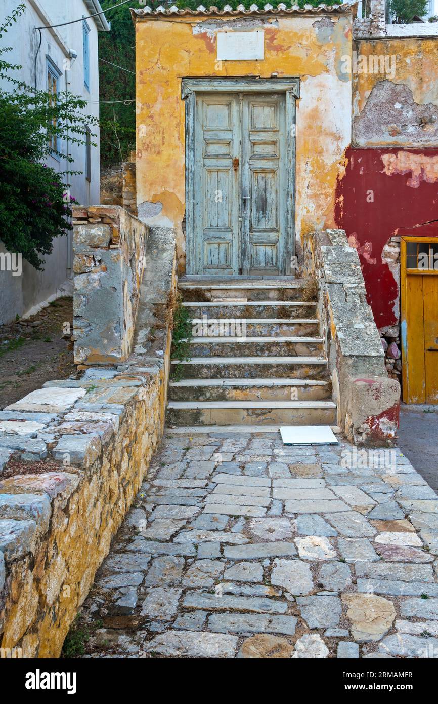 Eingang eines wunderschönen alten Hauses mit hellen, aber alten Farben auf abgenutzten Wänden, auf Hydra Insel, Griechenland, Europa. Stockfoto